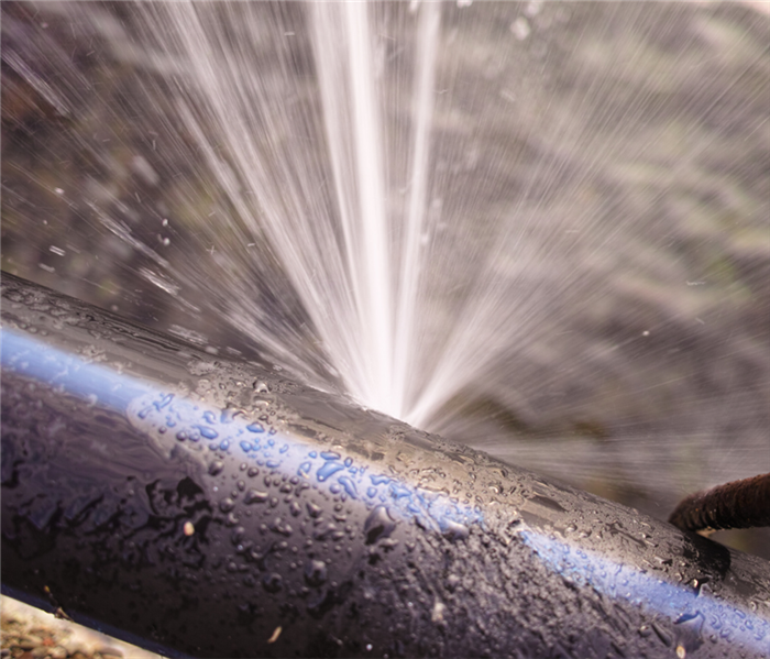 a large pipe spewing water due to a crack